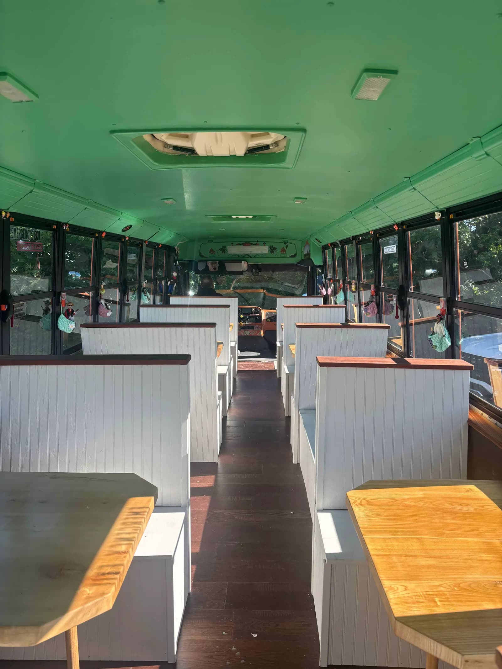Inside the bus — white church-pew booths and dark hardwood floors down the aisle
